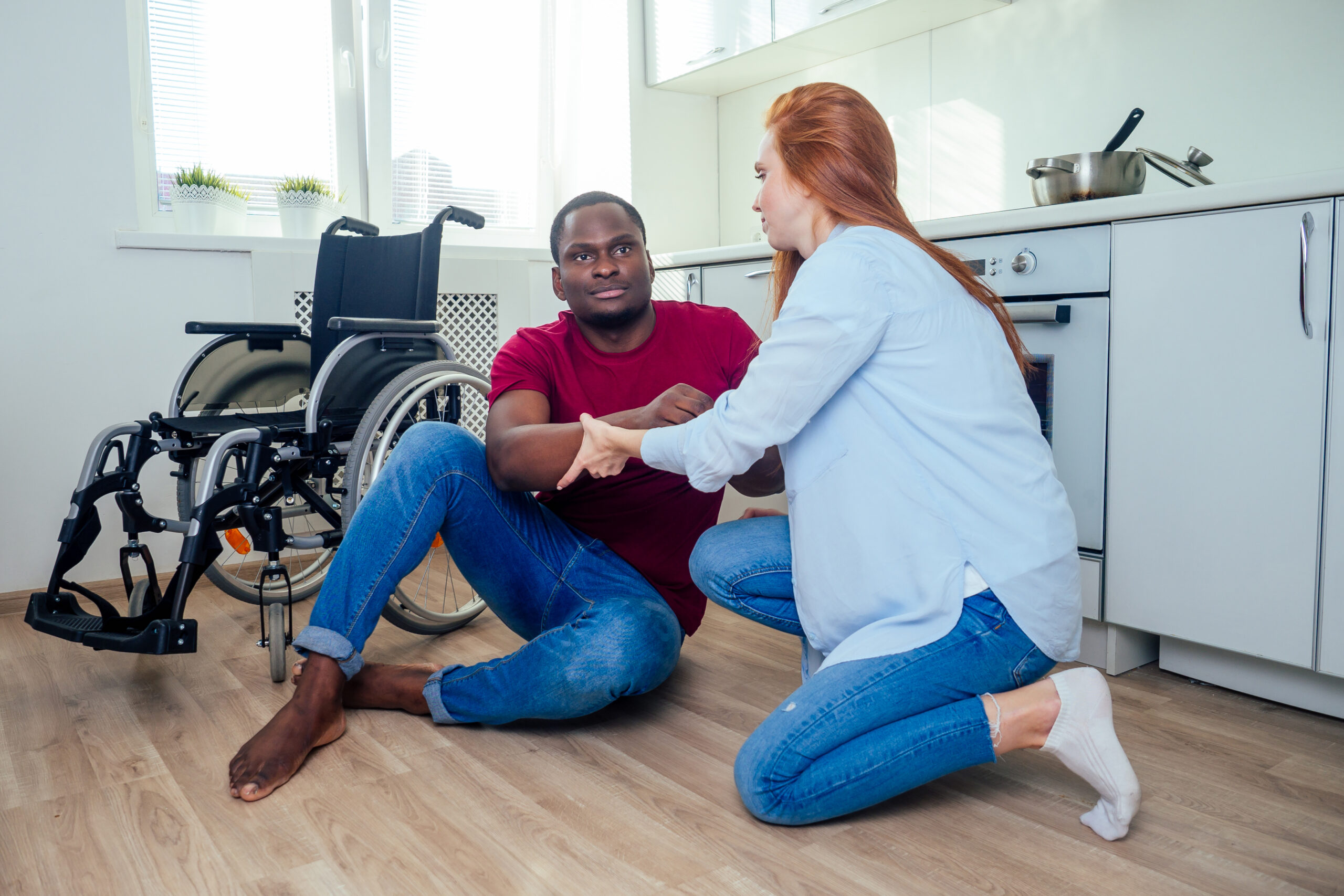 Young bearded handicapped african american man in wheelchair and his pretty wife at kichen
