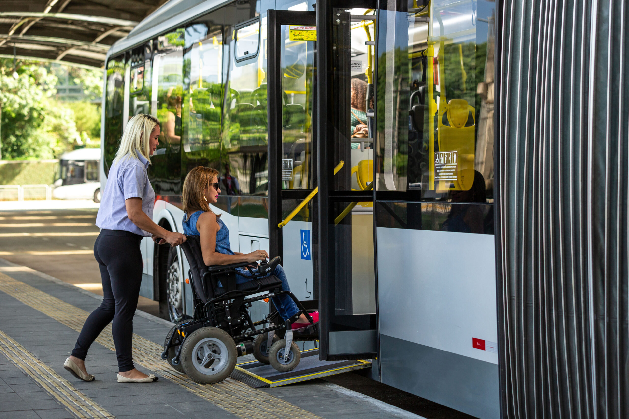 Assistant helps wheelchair user to board municipal bus